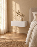 Three-quarter view of the white floating bedside table fixed to the wall above a clear floor
