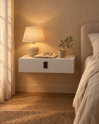 White floating bedside table with keypad lock with a lamp switched on and an open book in the evening