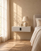 White floating bedside table with keypad lock with a ceramic lamp in warm morning light