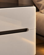 Close-up of the long black slot handle and the glossy white drawer fronts