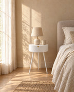 White round bedside table on three legs in morning light