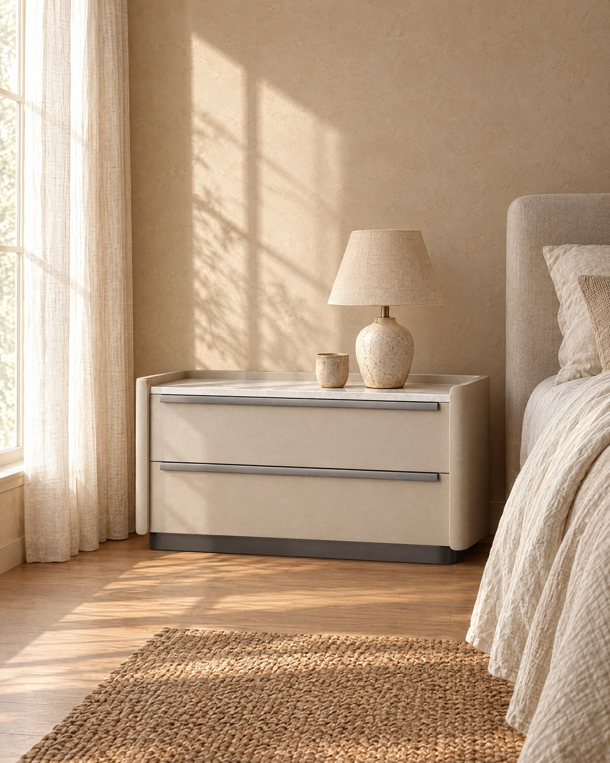 Wide cream bedside table with marble-effect top in warm morning light with window shadows on the wall