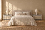 Pair of wide cream bedside tabless with marble-effect top on each side of a double bed