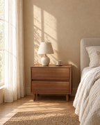 Wide walnut-effect bedside table with a ceramic lamp in morning light